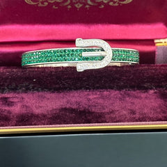 Emerald and clear rhinestone hinged bangle bracelet made of polished stainless steel with a modern belt buckle design, featuring sparkling accents and marked 316L S.Steel, photographed in excellent condition.