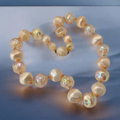 Vintage 1950s/1960s single-strand necklace featuring light peach hollow plastic beads alternating between opaque satin and iridescent transparent beads, finished with a snap clasp adorned with a light peach satin cabochon, signed Japan, in very good vintage condition.