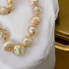 Vintage 1950s/1960s single-strand necklace featuring light peach hollow plastic beads alternating between opaque satin and iridescent transparent beads, finished with a snap clasp adorned with a light peach satin cabochon, signed Japan, in very good vintage condition.