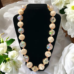 Vintage 1950s/1960s single-strand necklace featuring light peach hollow plastic beads alternating between opaque satin and iridescent transparent beads, finished with a snap clasp adorned with a light peach satin cabochon, signed Japan, in very good vintage condition.