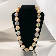 Vintage 1950s/1960s single-strand necklace featuring light peach hollow plastic beads alternating between opaque satin and iridescent transparent beads, finished with a snap clasp adorned with a light peach satin cabochon, signed Japan, in very good vintage condition.