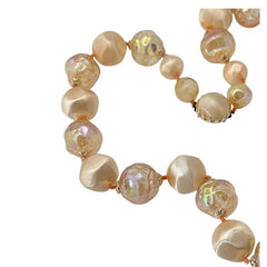 Vintage 1950s/1960s single-strand necklace featuring light peach hollow plastic beads alternating between opaque satin and iridescent transparent beads, finished with a snap clasp adorned with a light peach satin cabochon, signed Japan, in very good vintage condition.