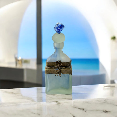 Vintage Romanian art glass perfume bottle from the 1990s, featuring frosted blue and green glass with a sculptural swirled stopper and bronze wire bow detail around the neck. Square base with a tapered neck; dauber slightly shortened due to breakage.