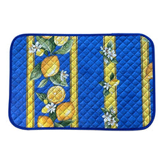 Reversible quilted cotton placemat in Lemons Blue by Tissus Toselli, featuring a blue background with vertical lemon garlands, green leaves, and white blossoms framed by golden diamond borders, identical on both sides, made in Provence."