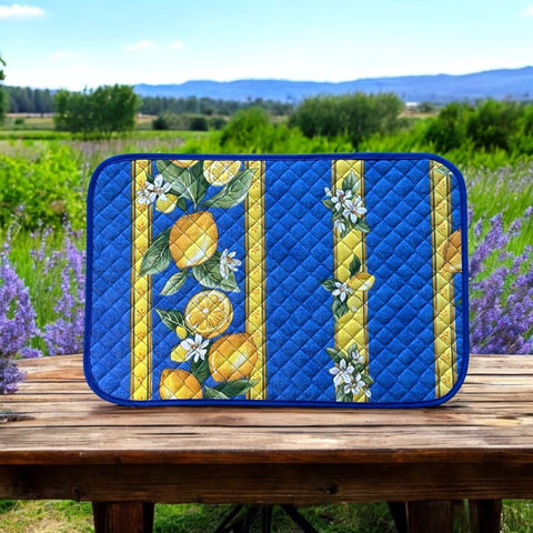 Reversible quilted cotton placemat in Lemons Blue by Tissus Toselli, featuring a blue background with vertical lemon garlands, green leaves, and white blossoms framed by golden diamond borders, identical on both sides, made in Provence."