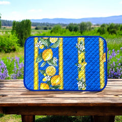 Reversible quilted cotton placemat in Lemons Blue by Tissus Toselli, featuring a blue background with vertical lemon garlands, green leaves, and white blossoms framed by golden diamond borders, identical on both sides, made in Provence."