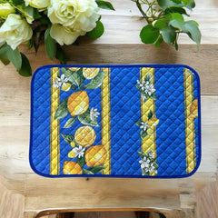 Reversible quilted cotton placemat in Lemons Blue by Tissus Toselli, featuring a blue background with vertical lemon garlands, green leaves, and white blossoms framed by golden diamond borders, identical on both sides, made in Provence."