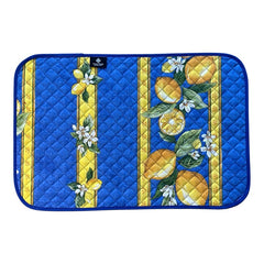 Reversible quilted cotton placemat in Lemons Blue by Tissus Toselli, featuring a blue background with vertical lemon garlands, green leaves, and white blossoms framed by golden diamond borders, identical on both sides, made in Provence."