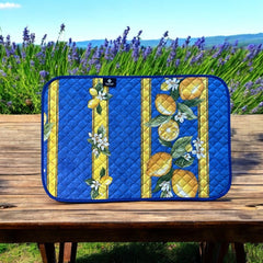Reversible quilted cotton placemat in Lemons Blue by Tissus Toselli, featuring a blue background with vertical lemon garlands, green leaves, and white blossoms framed by golden diamond borders, identical on both sides, made in Provence."