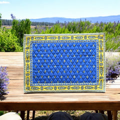Reversible quilted cotton placemat in Bastide Blue Yellow by Marat d’Avignon, featuring a bold blue floral diamond motif with yellow paisley borders on the front, and a blue background with golden yellow medallions on the reverse, crafted in Provence.