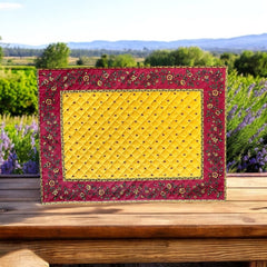 Reversible quilted cotton placemat in Fleurette Yellow Red by Marat d’Avignon, featuring a red diamond-quilted center with petite golden florals and yellow floral scroll borders on the front, and an allover red reverse with red floral accents, crafted in Provence.