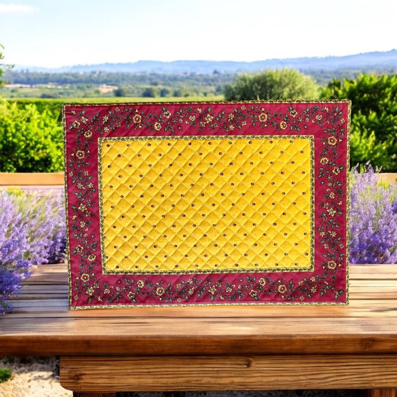 Reversible quilted cotton placemat in Fleurette Yellow Red by Marat d’Avignon, featuring a red diamond-quilted center with petite golden florals and yellow floral scroll borders on the front, and an allover red reverse with red floral accents, crafted in Provence.