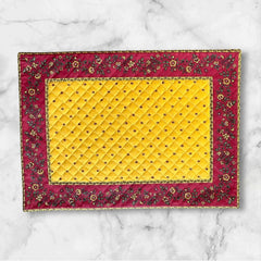 Reversible quilted cotton placemat in Fleurette Yellow Red by Marat d’Avignon, featuring a red diamond-quilted center with petite golden florals and yellow floral scroll borders on the front, and an allover red reverse with red floral accents, crafted in Provence.