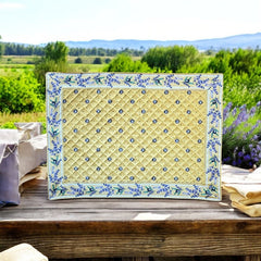 Reversible quilted cotton placemat in Lauris Light Yellow by Marat d’Avignon, featuring a pale yellow center with blue floral medallions and a border of lavender sprigs and olive branches, with a reverse side of soft yellow scattered with tiny blue and white blossoms, crafted in Provence.