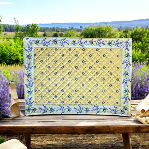 Reversible quilted cotton placemat in Lauris Light Yellow by Marat d’Avignon, featuring a pale yellow center with blue floral medallions and a border of lavender sprigs and olive branches, with a reverse side of soft yellow scattered with tiny blue and white blossoms, crafted in Provence.