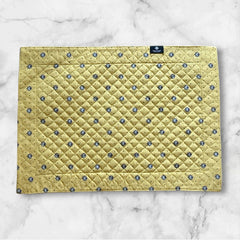 Reversible quilted cotton placemat in Lauris Light Yellow by Marat d’Avignon, featuring a pale yellow center with blue floral medallions and a border of lavender sprigs and olive branches, with a reverse side of soft yellow scattered with tiny blue and white blossoms, crafted in Provence.
