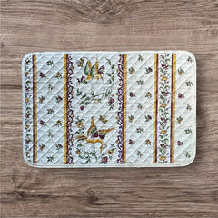 Provence Reversible quilted cotton placemat in Moustiers Red by Tissus Toselli, featuring traditional Provençal motifs inspired by Moustiers ceramics, with two birds in flight, floral garlands, and cream trim.