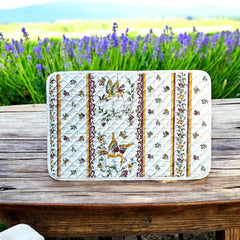 Provence Reversible quilted cotton placemat in Moustiers Red by Tissus Toselli, featuring traditional Provençal motifs inspired by Moustiers ceramics, with two birds in flight, floral garlands, and cream trim.