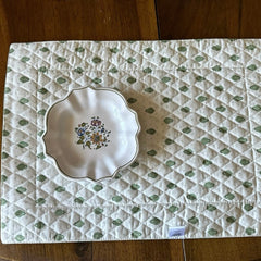 Reversible quilted cotton placemat in Bastide Green by Marat d’Avignon, featuring an ivory background with green floral medallions and scrolling vine borders on the front, and a white reverse with scattered green floral sprigs, crafted in Provence.