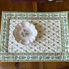 Reversible quilted cotton placemat in Bastide Green by Marat d’Avignon, featuring an ivory background with green floral medallions and scrolling vine borders on the front, and a white reverse with scattered green floral sprigs, crafted in Provence.