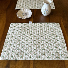 Reversible quilted cotton placemat in Bastide Green by Marat d’Avignon, featuring an ivory background with green floral medallions and scrolling vine borders on the front, and a white reverse with scattered green floral sprigs, crafted in Provence.