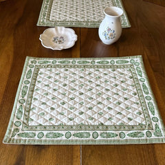 Reversible quilted cotton placemat in Bastide Green by Marat d’Avignon, featuring an ivory background with green floral medallions and scrolling vine borders on the front, and a white reverse with scattered green floral sprigs, crafted in Provence.