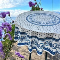 Round Provence-style cotton tablecloth by Le Cluny, featuring a blue and white floral design inspired by French elegance. Coated for easy cleaning, measures 70 inches in diameter, perfect for indoor and outdoor use.
