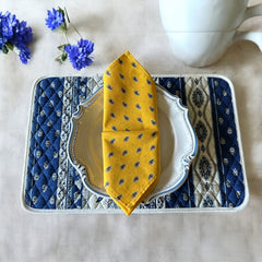 Provence cotton napkins featuring a yellow background with blue and yellow floral designs, part of the Avignon Collection from Marat d’Avignon made of 100% cotton, measuring 18" x 18", with vibrant, fade-resistant prints. Made in France.