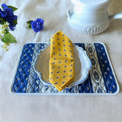 Provence cotton napkins featuring a yellow background with blue and yellow floral designs, part of the Avignon Collection from Marat d’Avignon made of 100% cotton, measuring 18" x 18", with vibrant, fade-resistant prints. Made in France.