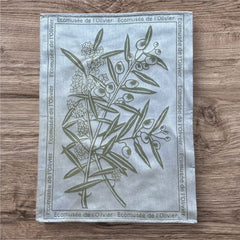 Provence tea towel featuring an olive branch with fruits and flowers at the center, framed by the repeated text 'L'Écomusée de l'Olivier.' Woven in olive green on a natural background with a 100% cotton composition, blending rustic charm and elegance.