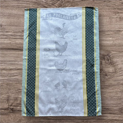Provence tea towel featuring Le Poulailler design with rooster, hen, eggs, chicks, and chicken motifs. Center in natural and light gray tones, bordered with yellow stripes, dark green checkered pattern, and lighter green edges. Made of 100% cotton, ideal for French farmyard decor.