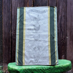 Provence tea towel featuring Le Poulailler design with rooster, hen, eggs, chicks, and chicken motifs. Center in natural and light gray tones, bordered with yellow stripes, dark green checkered pattern, and lighter green edges. Made of 100% cotton, ideal for French farmyard decor.