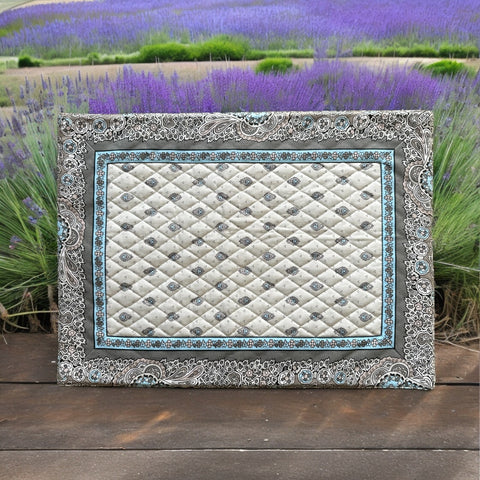 Reversible quilted cotton placemat in Bastide Blue Floral by Marat d’Avignon, featuring a soft blue and grey floral diamond motif on one side and a coordinating striped pattern on the reverse, crafted in Provence.