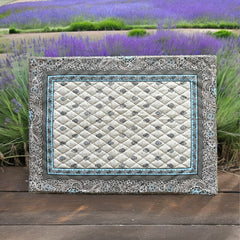 Reversible quilted cotton placemat in Bastide Blue Floral by Marat d’Avignon, featuring a soft blue and grey floral diamond motif on one side and a coordinating striped pattern on the reverse, crafted in Provence.