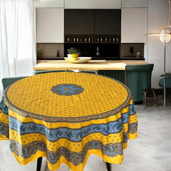 Round Provence-style coated cotton tablecloth by Marat d'Avignon, featuring a vibrant yellow background with blue and white floral patterns. Measures 70 inches in diameter, perfect for indoor and outdoor use, and easy to clean.