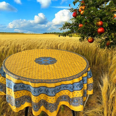 Round Provence-style coated cotton tablecloth by Marat d'Avignon, featuring a vibrant yellow background with blue and white floral patterns. Measures 70 inches in diameter, perfect for indoor and outdoor use, and easy to clean.