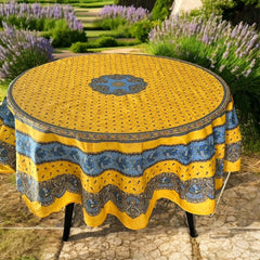 Round Provence-style coated cotton tablecloth by Marat d'Avignon, featuring a vibrant yellow background with blue and white floral patterns. Measures 70 inches in diameter, perfect for indoor and outdoor use, and easy to clean.