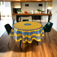 Round Provence-style coated cotton tablecloth by Marat d'Avignon, featuring a vibrant yellow background with blue and white floral patterns. Measures 70 inches in diameter, perfect for indoor and outdoor use, and easy to clean.
