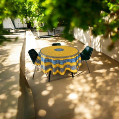 Round Provence-style coated cotton tablecloth by Marat d'Avignon, featuring a vibrant yellow background with blue and white floral patterns. Measures 70 inches in diameter, perfect for indoor and outdoor use, and easy to clean.