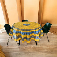 Round Provence-style coated cotton tablecloth by Marat d'Avignon, featuring a vibrant yellow background with blue and white floral patterns. Measures 70 inches in diameter, perfect for indoor and outdoor use, and easy to clean.