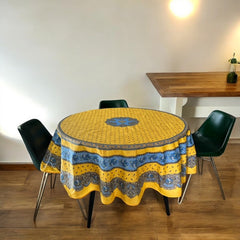 Round Provence-style coated cotton tablecloth by Marat d'Avignon, featuring a vibrant yellow background with blue and white floral patterns. Measures 70 inches in diameter, perfect for indoor and outdoor use, and easy to clean.