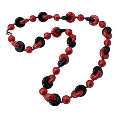 A vintage necklace featuring marbleized red and shiny black plastic beads from the 1990s. The design includes interlocking red and black donut-shaped beads with a round marbleized red bead between each combination. A bold and artistic statement accessory in very good vintage condition.