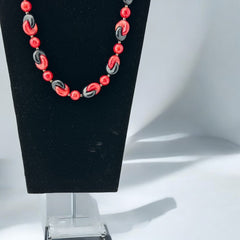 A vintage necklace featuring marbleized red and shiny black plastic beads from the 1990s. The design includes interlocking red and black donut-shaped beads with a round marbleized red bead between each combination. A bold and artistic statement accessory in very good vintage condition.