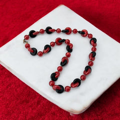 A vintage necklace featuring marbleized red and shiny black plastic beads from the 1990s. The design includes interlocking red and black donut-shaped beads with a round marbleized red bead between each combination. A bold and artistic statement accessory in very good vintage condition.