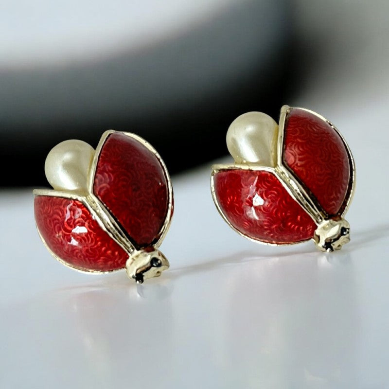 Set of two vintage 1990s ladybug scatter brooches featuring red guilloché enamel wings with a delicate engraved pattern, gold-tone metal, black enamel eyes, and pear-shaped faux pearls nestled between the wings. These whimsical yet elegant brooches add a charming touch to any outfit. Unsigned and in very good vintage condition.