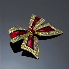 Vintage 1990s bow brooch in red enamel and gold-tone metal with pavé rhinestones, shown worn or displayed to highlight its elegant design and excellent condition.