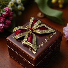 Vintage 1990s bow brooch in red enamel and gold-tone metal with pavé rhinestones, shown worn or displayed to highlight its elegant design and excellent condition.