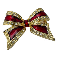 Vintage 1990s bow brooch in red enamel and gold-tone metal with pavé rhinestones, shown worn or displayed to highlight its elegant design and excellent condition.
