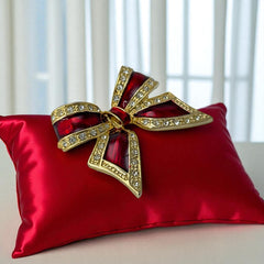 Vintage 1990s bow brooch in red enamel and gold-tone metal with pavé rhinestones, shown worn or displayed to highlight its elegant design and excellent condition.