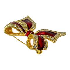 Vintage 1990s bow brooch in red enamel and gold-tone metal with pavé rhinestones, shown worn or displayed to highlight its elegant design and excellent condition.